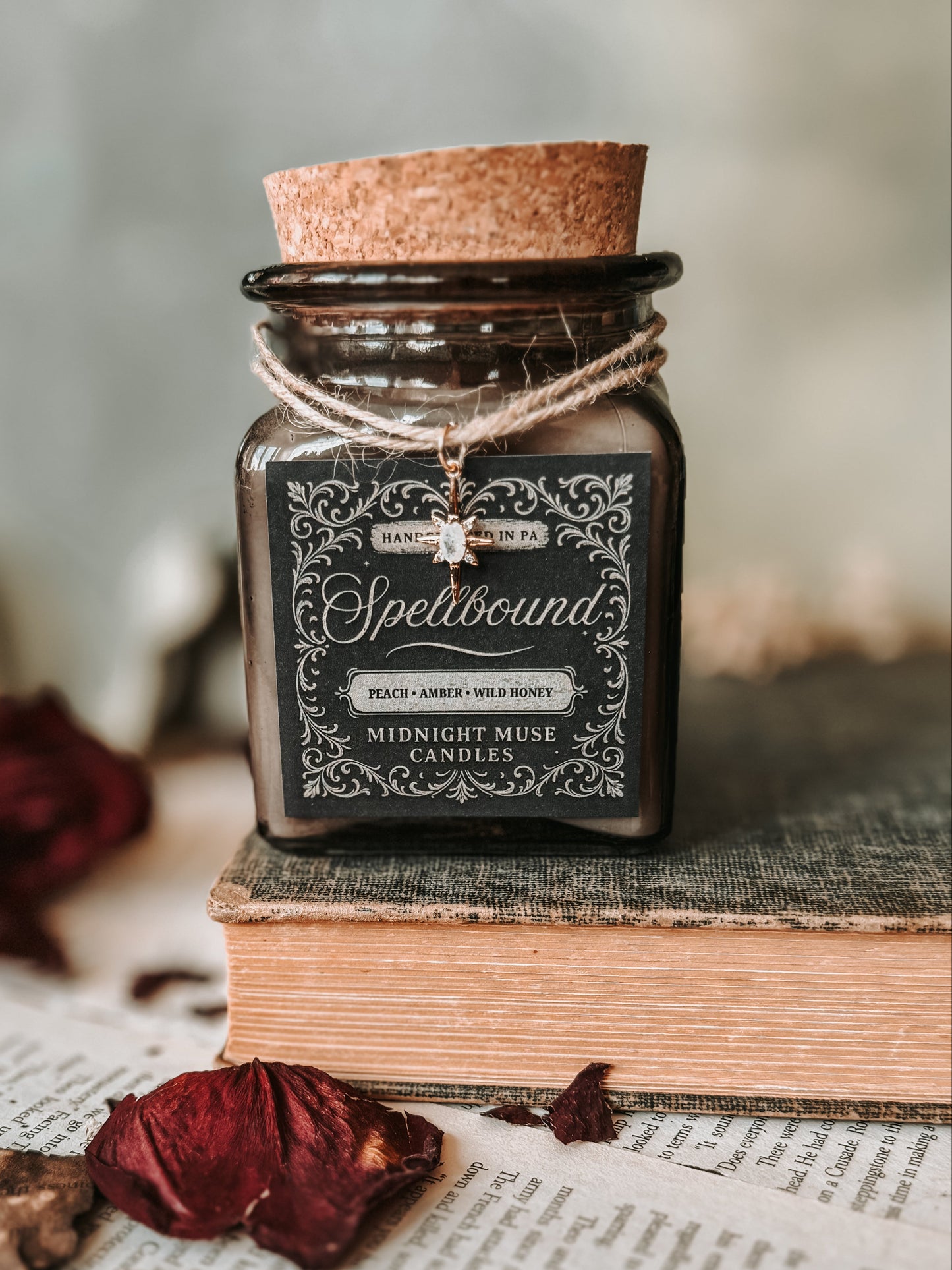 Candle labeled 'Spellbound' on an old book with dried leaves and a key