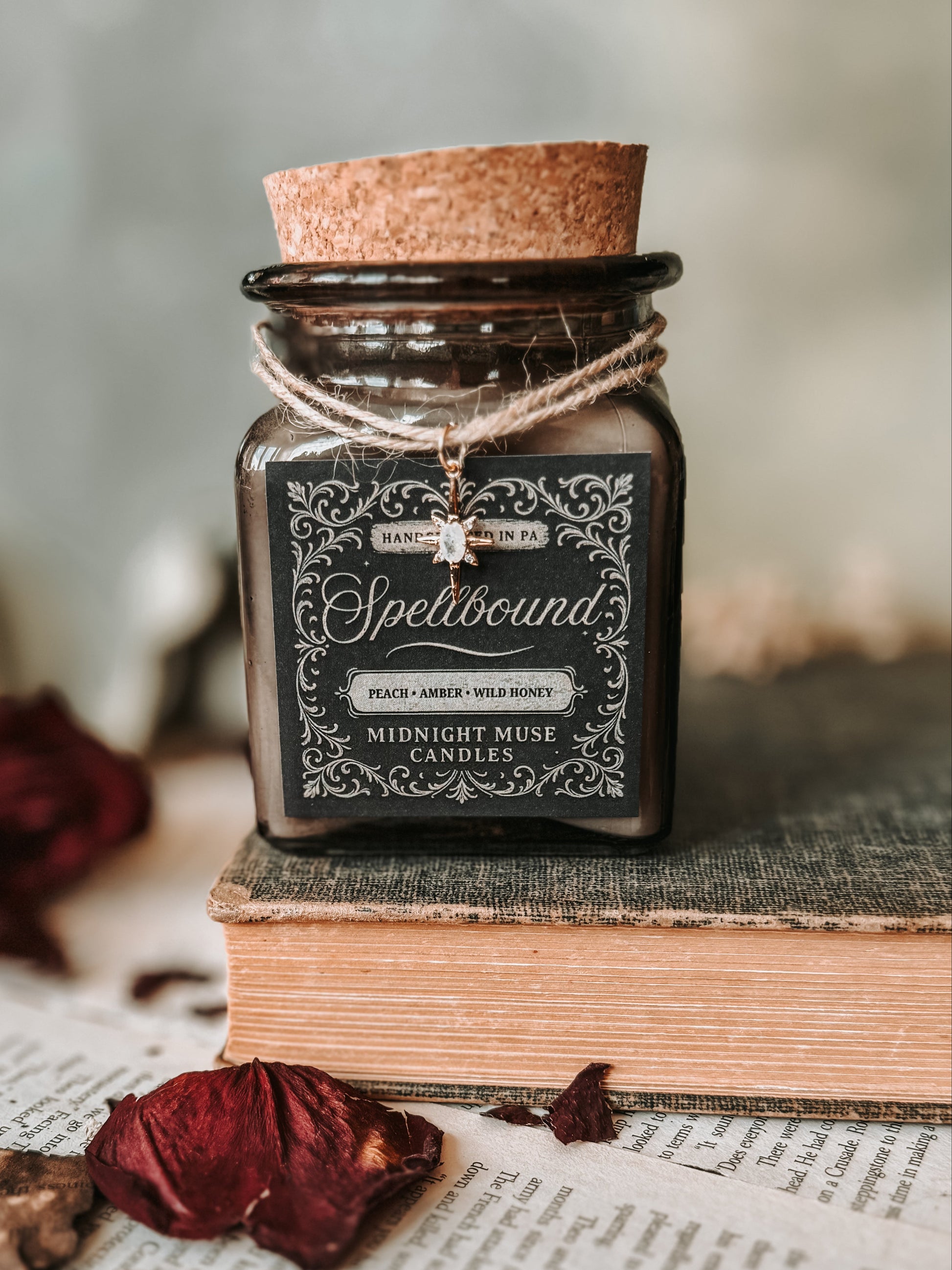 Candle labeled 'Spellbound' on an old book with dried leaves and a key